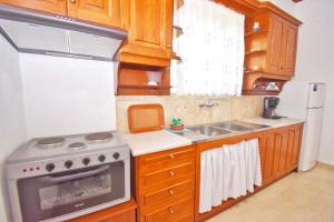a kitchen with wooden cabinets and a stove and a sink at Ninas Cottage in Línia