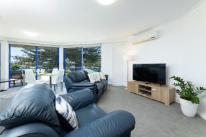a living room with couches and a flat screen tv at Heritage 201 in Tuncurry