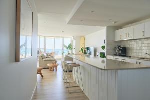 uma cozinha e sala de estar com um balcão e cadeiras em Foreshore Beachfront Apartments em Gold Coast