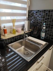 a stainless steel sink in a kitchen with black tiles at D&A Apartament in Szczecinek
