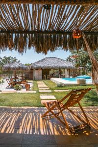 um pátio com 2 cadeiras e uma cabana com piscina em Vila Castanheiras em Barra Grande