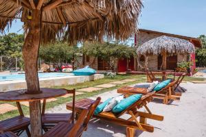 een groep houten stoelen met kussens en een paraplu bij Vila Castanheiras in Barra Grande