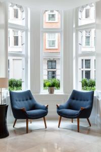 duas cadeiras azuis num quarto com janelas em Radisson Blu Kenilworth Hotel, London em Londres