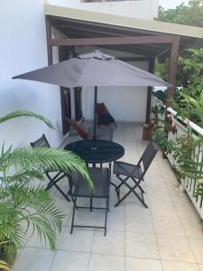 a table and chairs under an umbrella on a patio at Logement vacances Gissac Sainte-Anne in Sainte-Anne