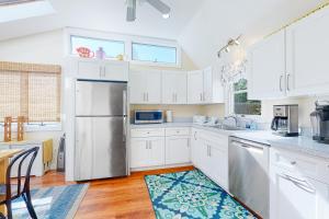 a kitchen with white cabinets and a stainless steel refrigerator at Canary Cottage in Oak Bluffs
