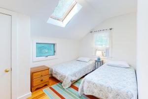 a bedroom with two beds and a window at Canary Cottage in Oak Bluffs