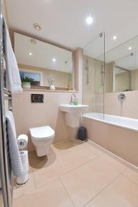 een badkamer met een wastafel, een toilet en een bad bij Lavender House Apartments Limehouse Docklands in Londen