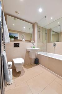 een badkamer met een toilet, een wastafel en een bad bij Lavender House Apartments Limehouse Docklands in Londen