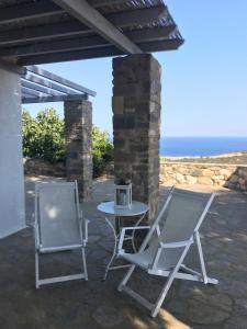 two chairs and a table on a patio with the ocean at Idyllic Sea Views for 2 in Aspro Chorio Paros