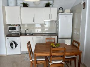 uma cozinha com armários brancos e uma mesa e cadeiras de madeira em Tenerife apartamento Sun Beach & Relax em Puertito de Güímar