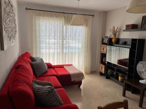 uma sala de estar com um sofá vermelho em frente a uma janela em Tenerife apartamento Sun Beach & Relax em Puertito de Güímar