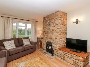 a living room with a couch and a stone fireplace at Lanes End in Sherborne