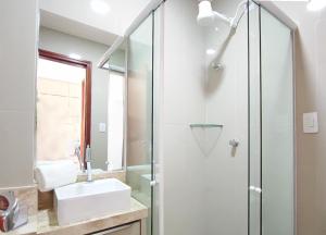 a bathroom with a sink and a glass shower at House Aconchegante Ponta Negra in Natal