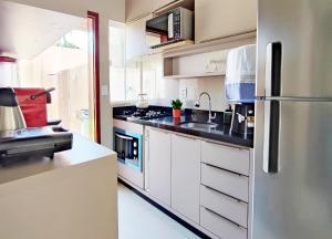 a kitchen with white cabinets and a stainless steel refrigerator at House Aconchegante Ponta Negra in Natal