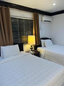 a bedroom with two beds and a lamp and a window at Colony Club Inn & Suites in Nassau
