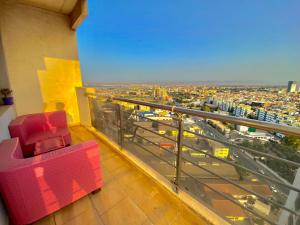 Tulipe appartement في وهران: كرسي احمر جالس على شرفة المبنى