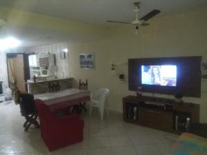 a living room with a flat screen tv and a table at Arraial do Cabo in Arraial do Cabo