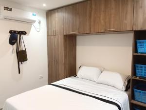 1 dormitorio con 1 cama y armario de madera en Confortable, en Guayaquil