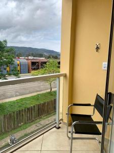 a chair sitting on a balcony with a view of a train at Lindo apartamento em frente a UFOP com garagem in Ouro Preto