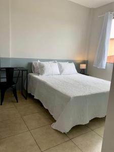 a bedroom with a white bed and a table at Lindo apartamento em frente a UFOP com garagem in Ouro Preto