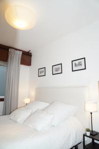 een wit bed met witte kussens in een slaapkamer bij Amazing Location CORUÑA DOWNTOWN in A Coruña