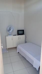 a white bedroom with a bed and a fan at Pousada Nova in Montes Claros