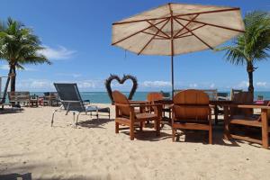 - une table, des chaises et un parasol sur la plage dans l'établissement Villa Maravilha, à Arraial d'Ajuda