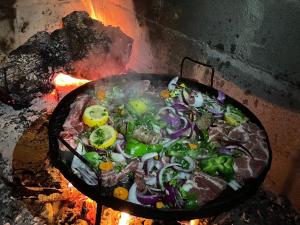 a pan of food is cooking on a fire at Mirlo’s hostel in Futaleufú