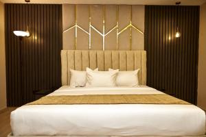 um quarto com uma cama grande e almofadas brancas em Mayfair Hotel Wuse2 Abuja em Abuja