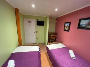 2 camas en una habitación con paredes moradas y verdes en Hostal Recuerdos de Familia, en Valparaíso