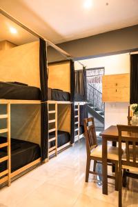 a room with bunk beds and a table and chairs at Maui Hostels Playa del Carmen in Playa del Carmen