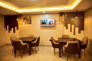 uma sala de jantar com duas mesas e cadeiras e uma televisão em Mayfair Hotel Wuse2 Abuja em Abuja
