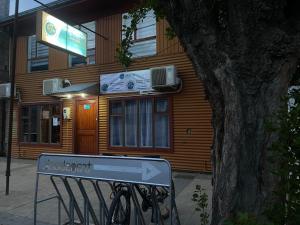 een bord voor een gebouw voor een boom bij World's End Hostal in Puerto Natales