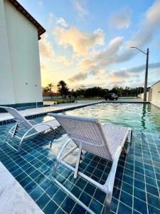 two chairs sitting next to a swimming pool at Lençois Confort in Barreirinhas