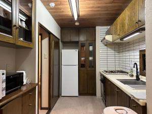 札幌市にあるLIT’S INN Sapporoのキッチン(白い冷蔵庫、木製キャビネット付)
