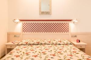 a bedroom with a bed with a floral bedspread at Hotel Katja in Bibione