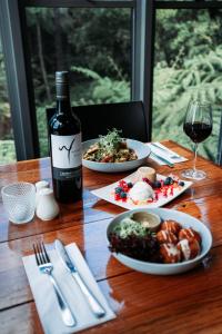 una mesa con dos platos de comida y una botella de vino en Binna Burra Sky Lodges, en Beechmont