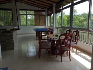 comedor con mesa, sillas y ventanas en FINCA LA AMISTAD, en Anapoima