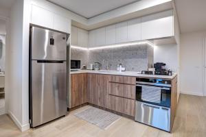 La cuisine est équipée d'un réfrigérateur en acier inoxydable et de placards en bois. dans l'établissement The Hamptons - Lux 2 Bed 2 Bath, Pool - Central Location, à Canberra