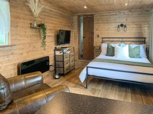 Boyton的住宿－Uk41510 - The Cabin，一间卧室配有一张床、一张沙发和一台电视