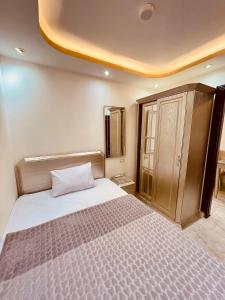 a bedroom with a large bed and a cabinet at El mansour hotel apartmen 84 in Mansoura