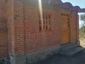 un edificio de ladrillo con puerta y ventana en CABAÑAS TLAXCO LA LOMA, en Tlaxco de Morelos