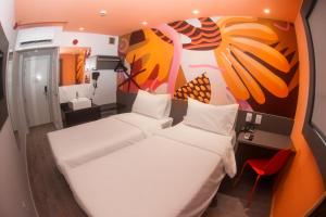 a room with two beds and a wall with a painting at Ibis Styles Garanhuns in Garanhuns
