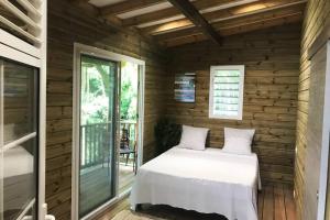 1 dormitorio con 1 cama en una pared de madera en Chalet Colibri , Les ANSES d'ARLET 200 m plage en Les Anses-dʼArlets