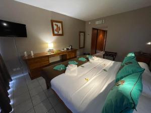 Cette chambre comprend un grand lit avec des oreillers verts. dans l'établissement Tiki Hôtel - Hôtel d'application du Lycée de Tahiti, à Punaauia