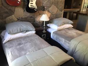 dwa łóżka w pokoju z gitarą na ścianie w obiekcie Loft Chacras de Coria w mieście Chacras de Coria