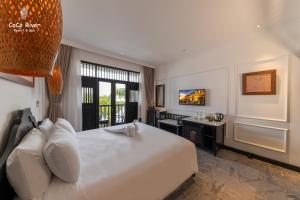 a bedroom with a large white bed and a desk at Hoi An Coco River Resort & Spa in Hoi An