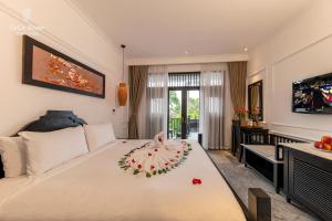 een slaapkamer met een bed met een bloemstuk erop bij Hoi An Coco River Resort & Spa in Hội An