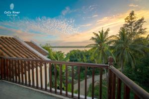 balcón con vistas al agua y a las palmeras en Hoi An Coco River Resort & Spa, en Hoi An
