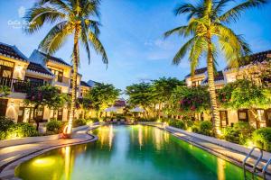 a pool in the middle of a resort with palm trees at Hoi An Coco River Resort & Spa in Hoi An